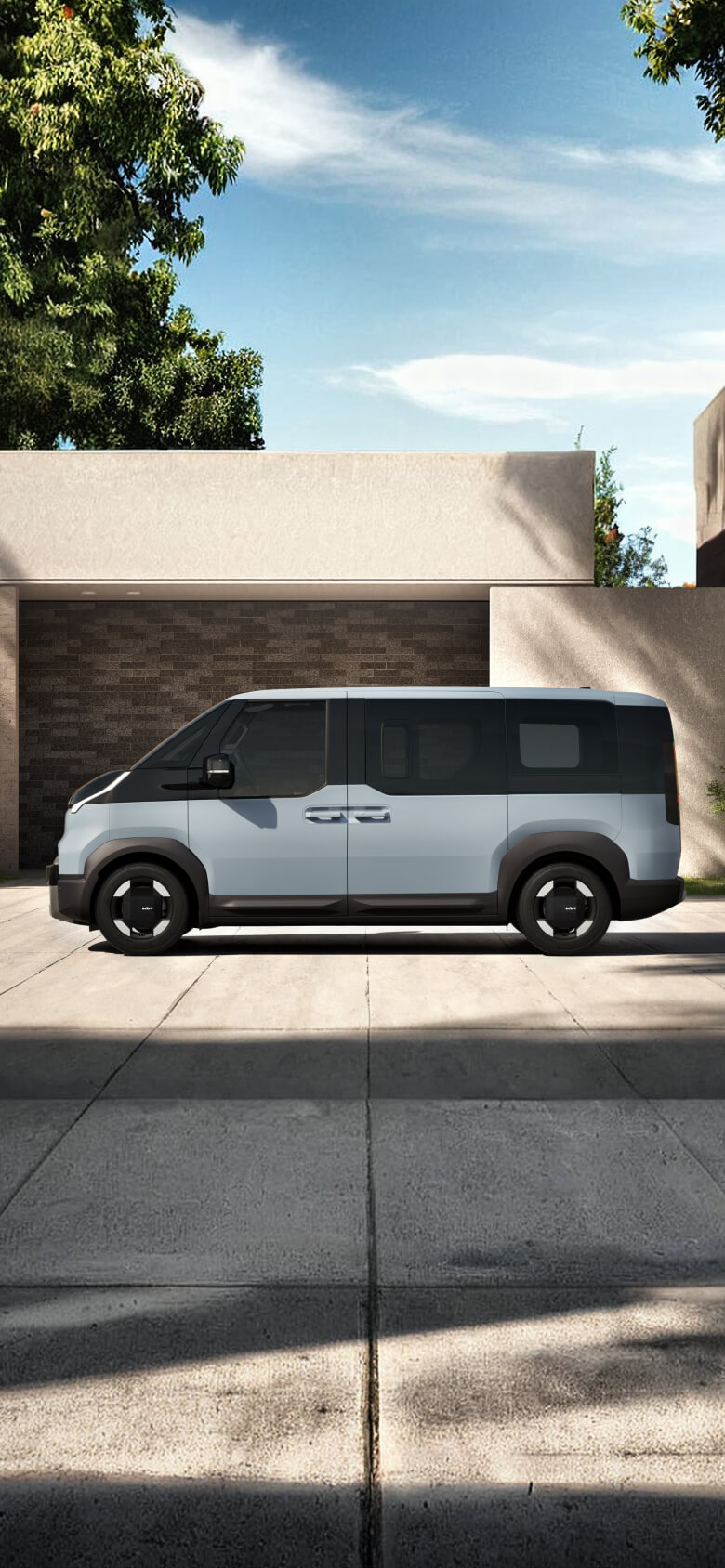 Front view of the Kia PV5 Passenger driving through an urban coastal area