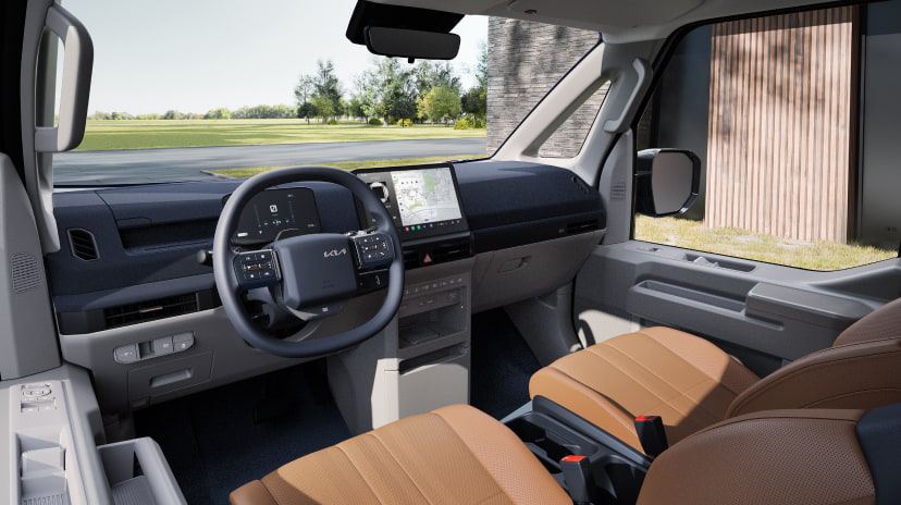 Fahrerseitiger Innenraum des Kia PV5 Passenger mit braunen Sitzen und digitaler Cockpitanzeige