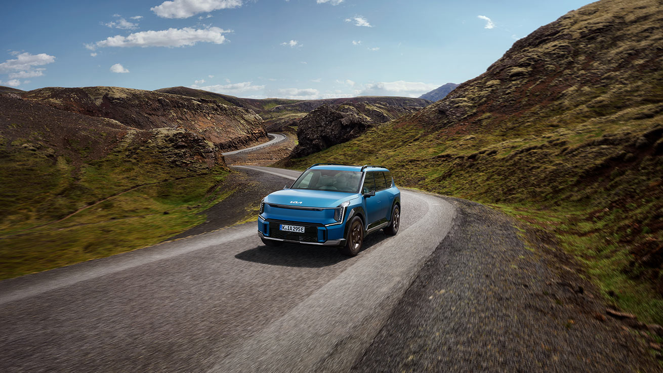 Ein blauer Kia EV9 fährt auf einer Landstraße